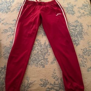 red adidas sweatpants. white stripes on the side of each leg, pockets, cuff legs